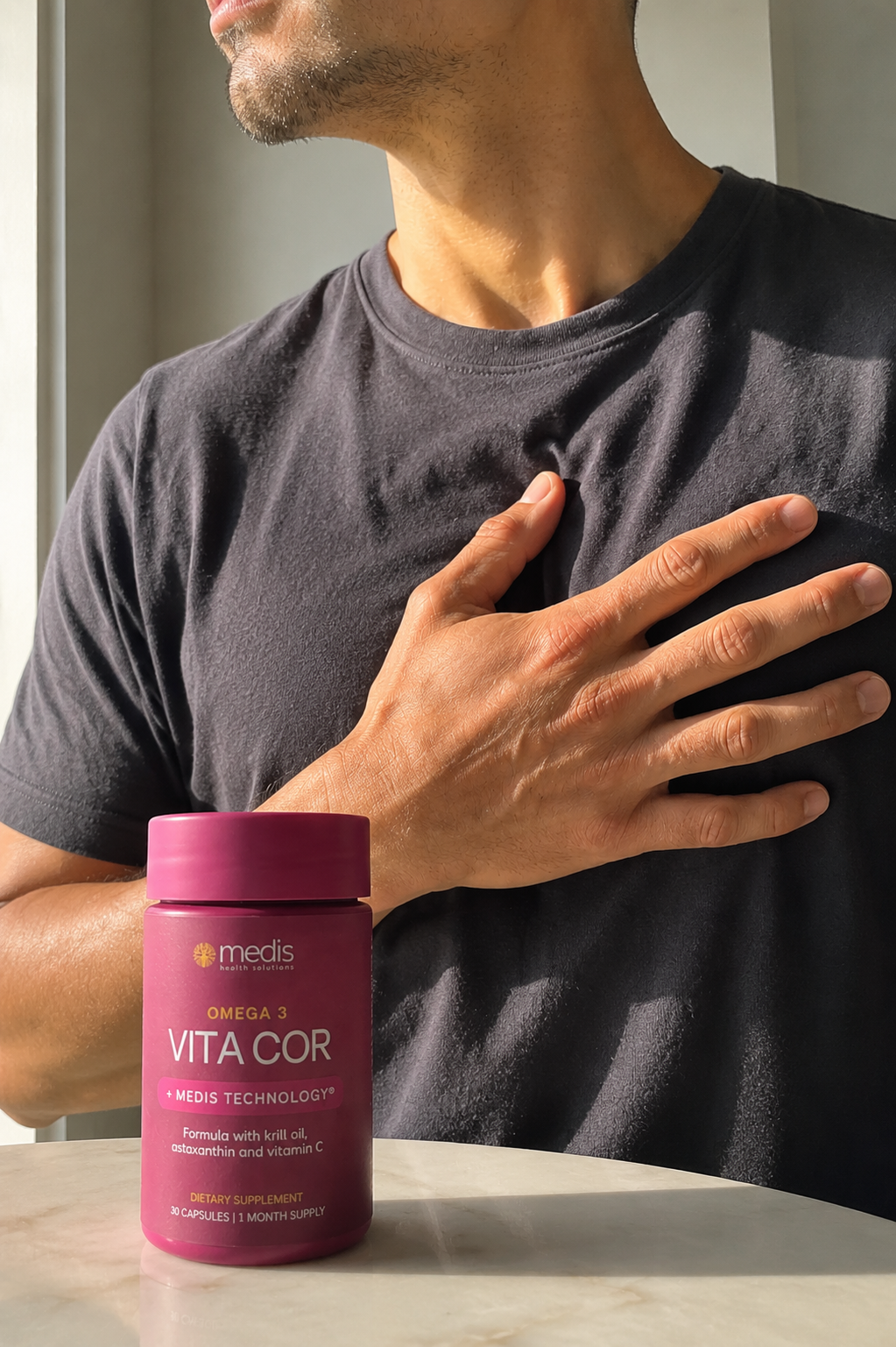Man holding a bottle of Medis Vitacor supplement on a marble surface.